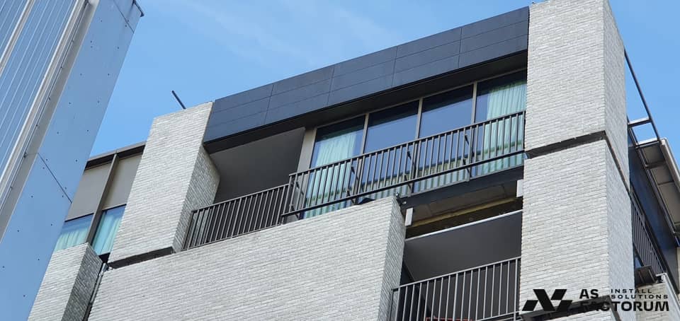 Balconies with metal railings on the light brick facade of an apartment block