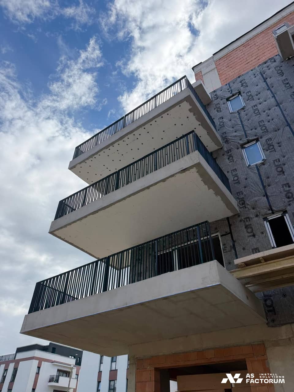 Concrete balconies fitted with dark steel vertical-bar railings on a building under construction