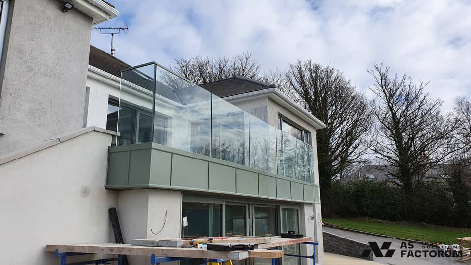 Balcony with a glass balustrade above a metal-clad parapet on a house