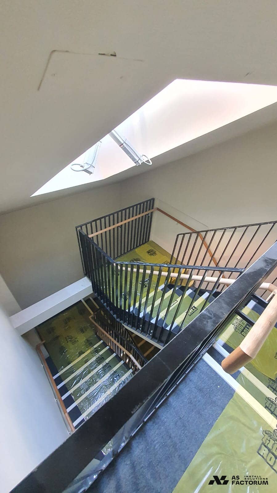 Black steel stair balustrade with yellow protective film still covering the handrail and steps