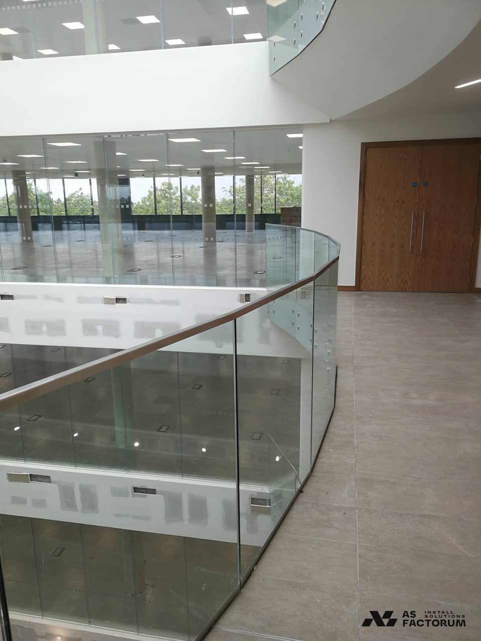 Curved glass balustrade with a handrail, on an interior gallery