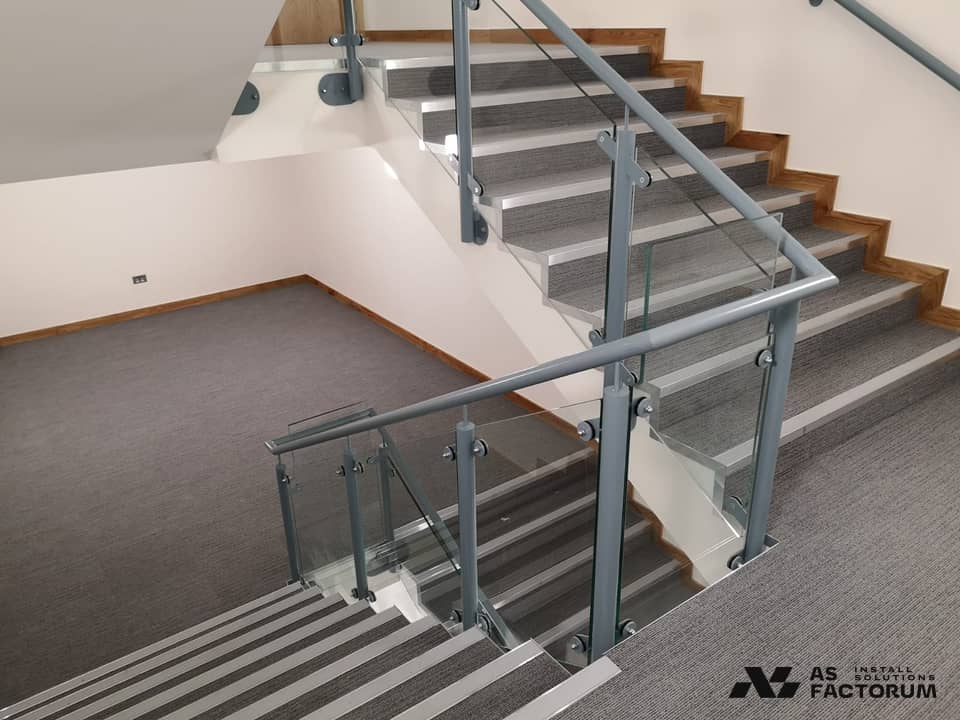 Glass balustrade with metal posts and handrail on a two-flight staircase