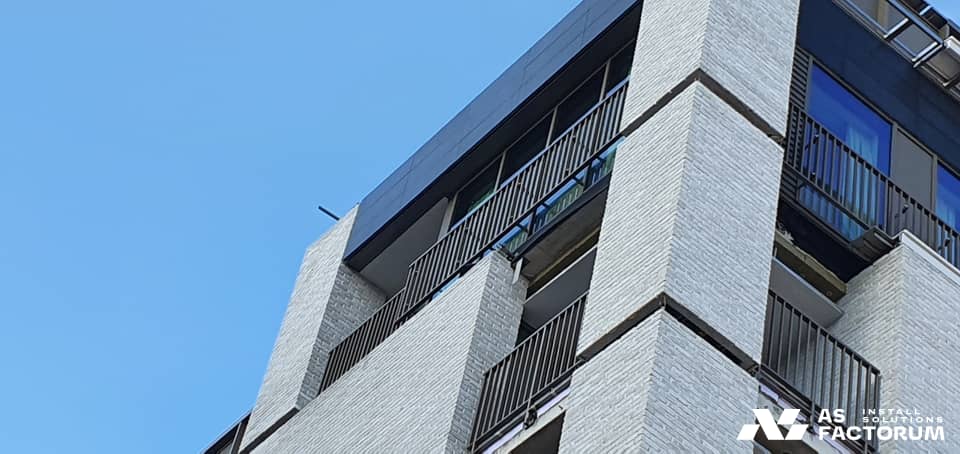 Black metal balcony railings at the corner of a building, seen from below