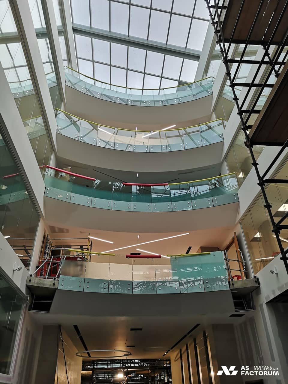 Glass balustrades across several atrium levels, seen from below under a glazed roof