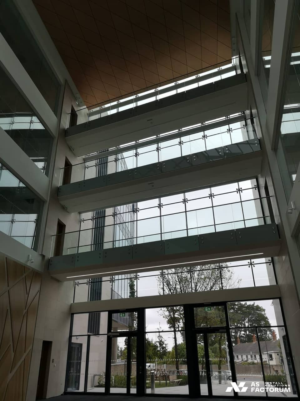 Point-fixed glass balustrades on the balconies of a tall atrium, seen from below