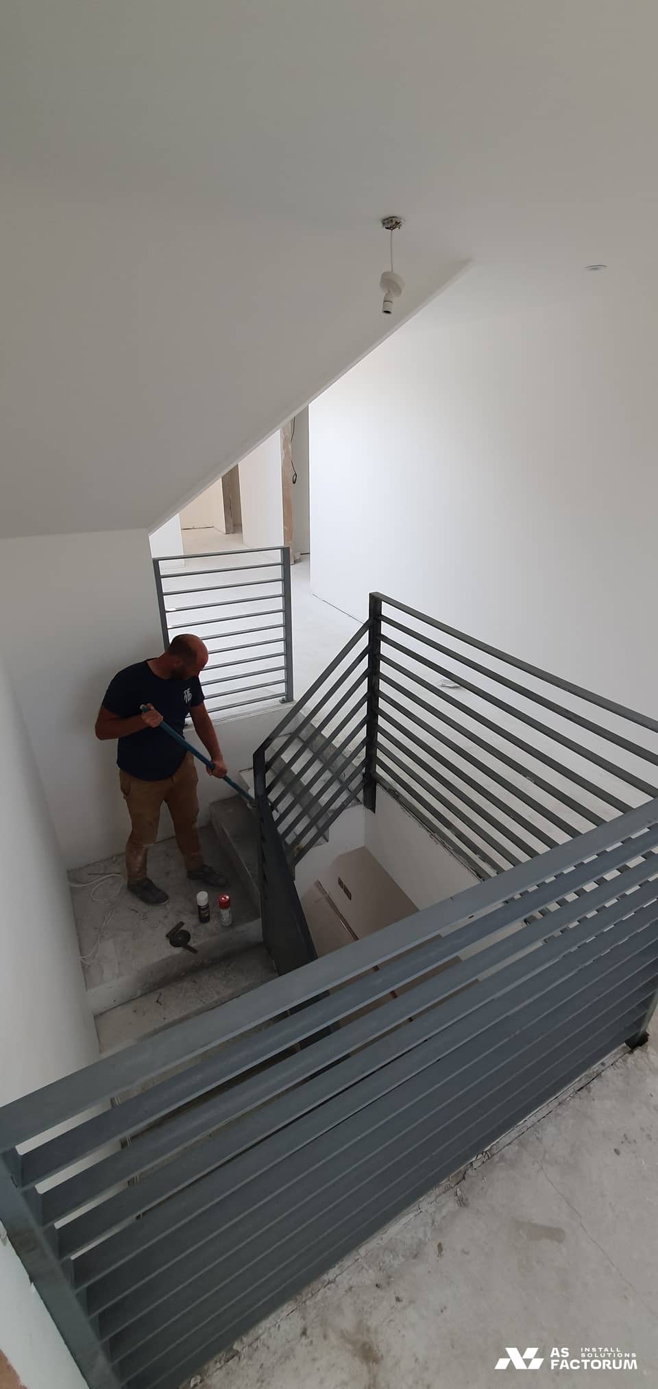 Worker finishing a horizontal-bar staircase balustrade in a building under fit-out