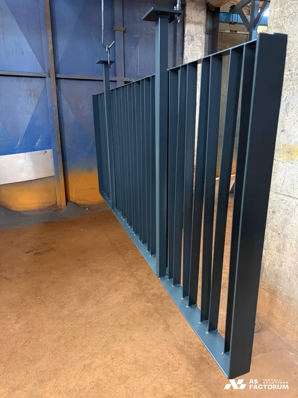 Dark grey painted vertical-bar railing panels hanging inside a workshop