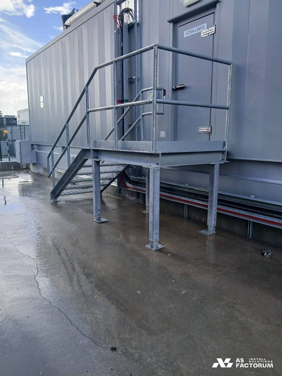 Galvanised grated platform raised on legs, with its access stair and railings