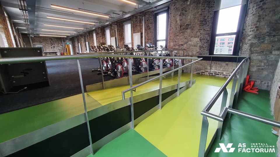 Ramp with metal railings in a room with exercise bikes, in an old brick building
