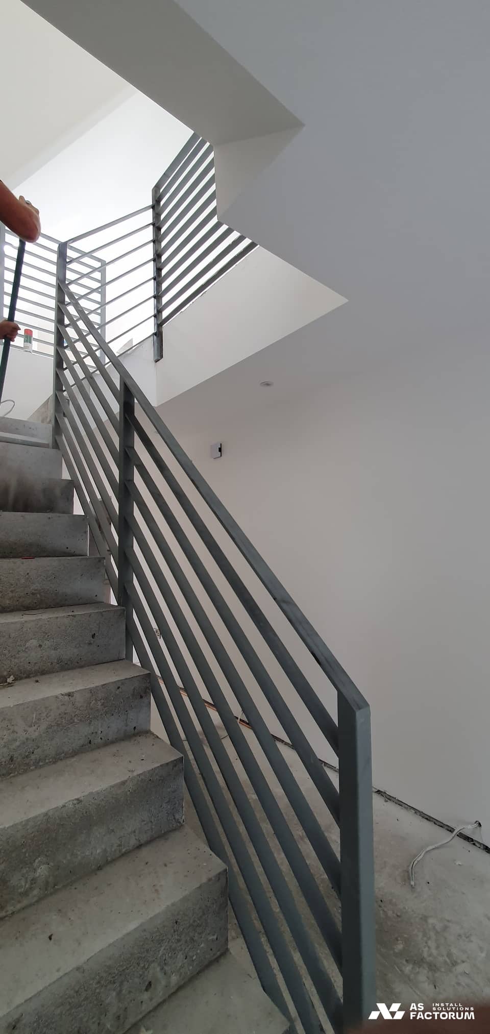 Staircase with a horizontal-bar metal balustrade in a building being finished