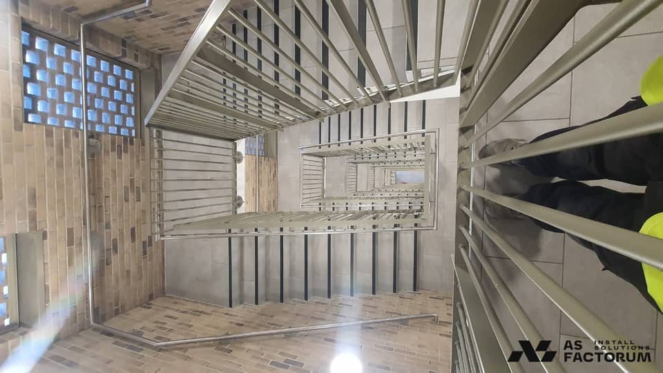 Brick stairwell with a grey-olive round-bar balustrade and stainless steel handrail