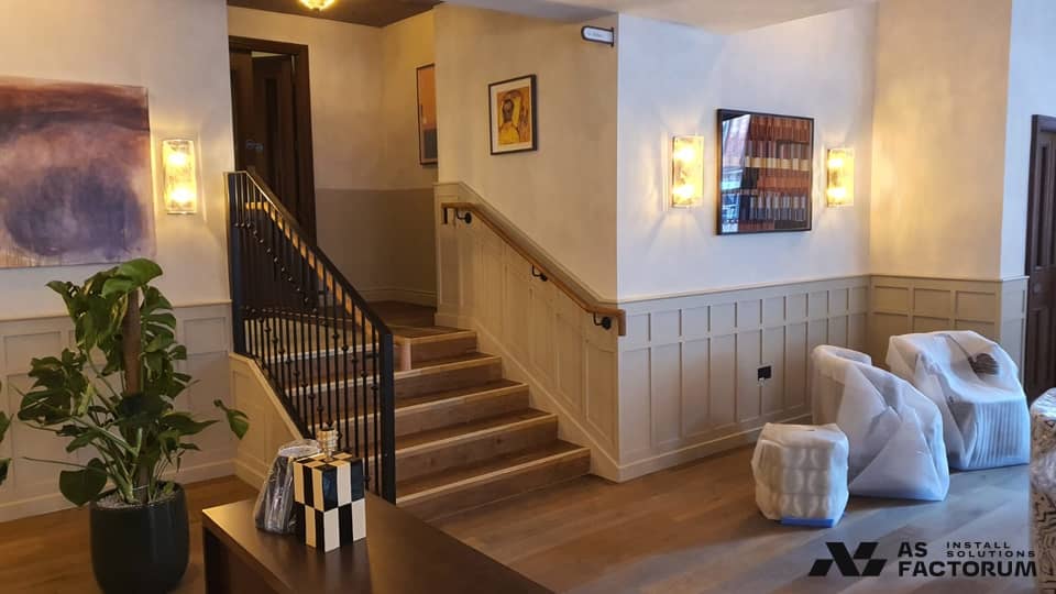 Lobby staircase with a black steel balustrade, timber handrail and panelled walls