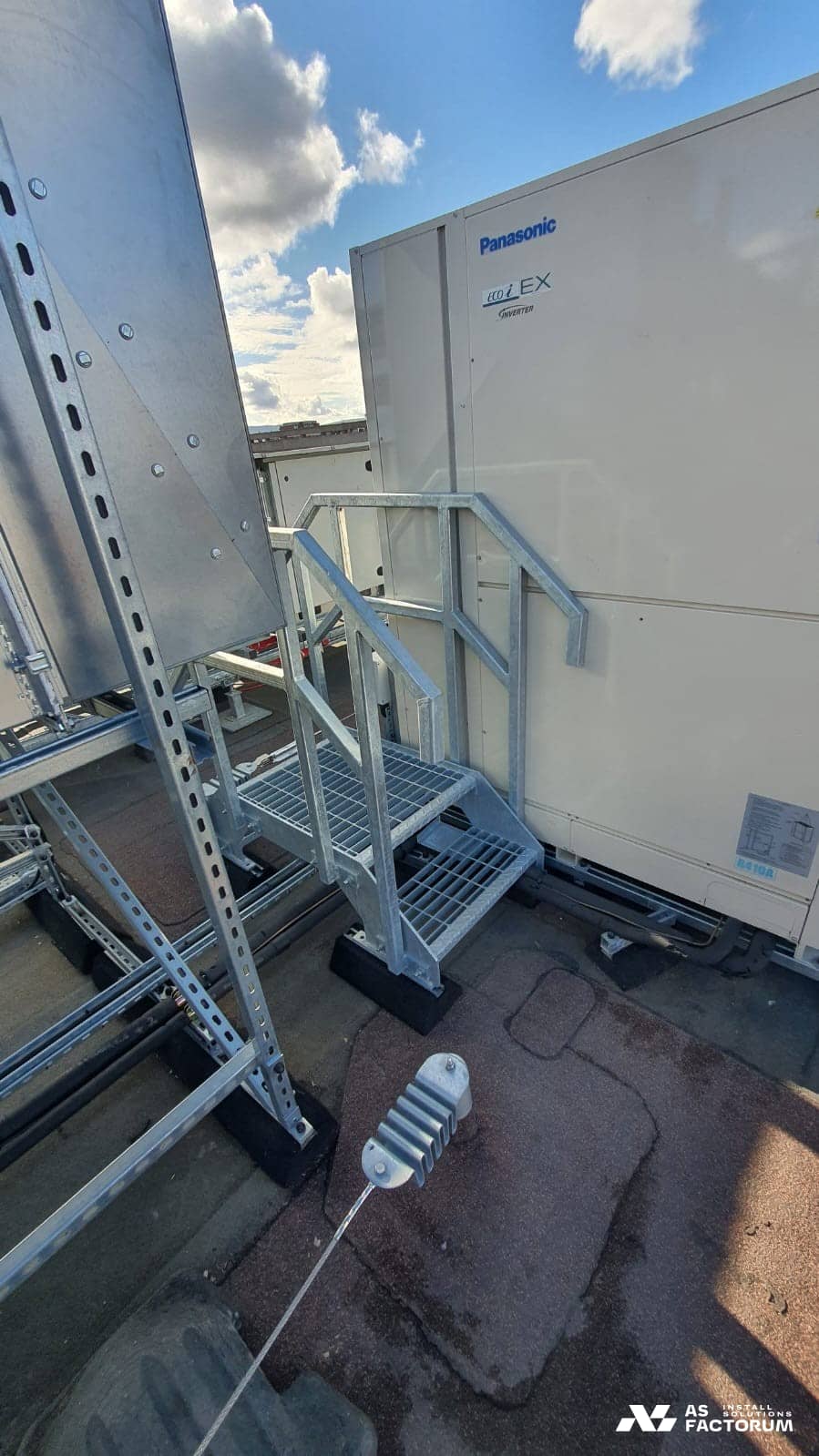 Small galvanised stair beside an outdoor HVAC unit, providing service access