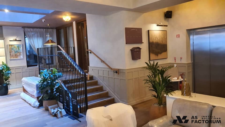 Lobby stair steps flanked by a black metal balustrade topped with a timber handrail