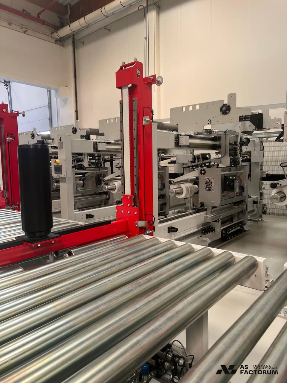 Close view of a roller conveyor and a packaging machine installed in a hall