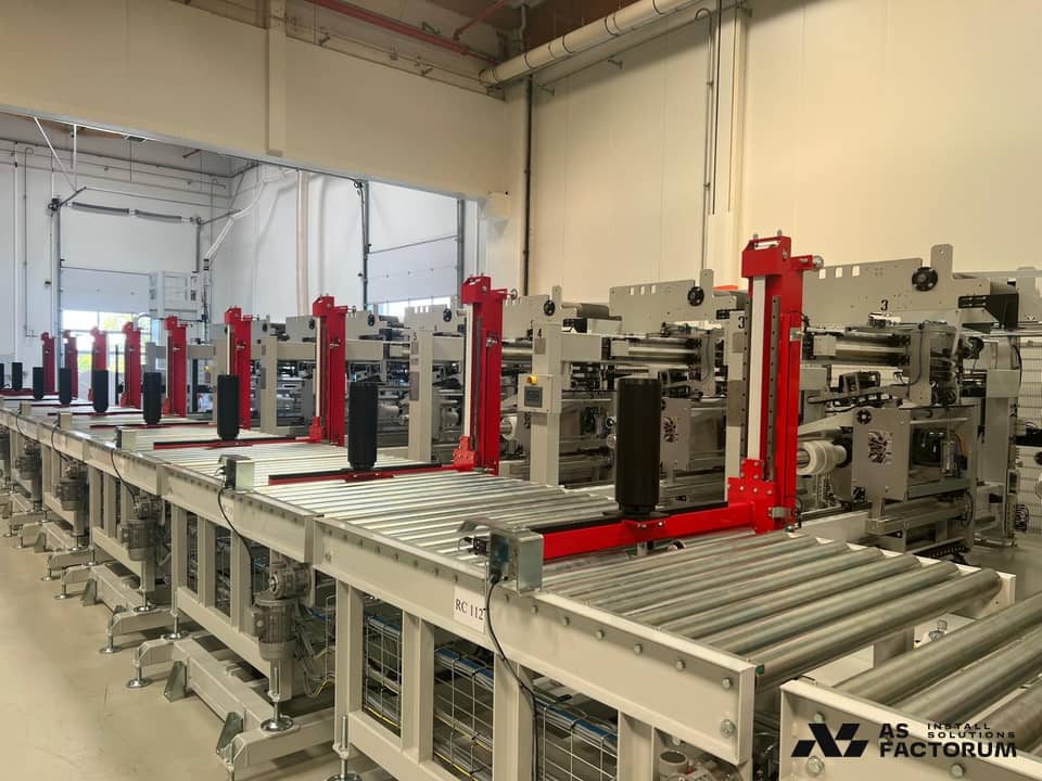 Row of packaging modules along a roller conveyor in a production hall