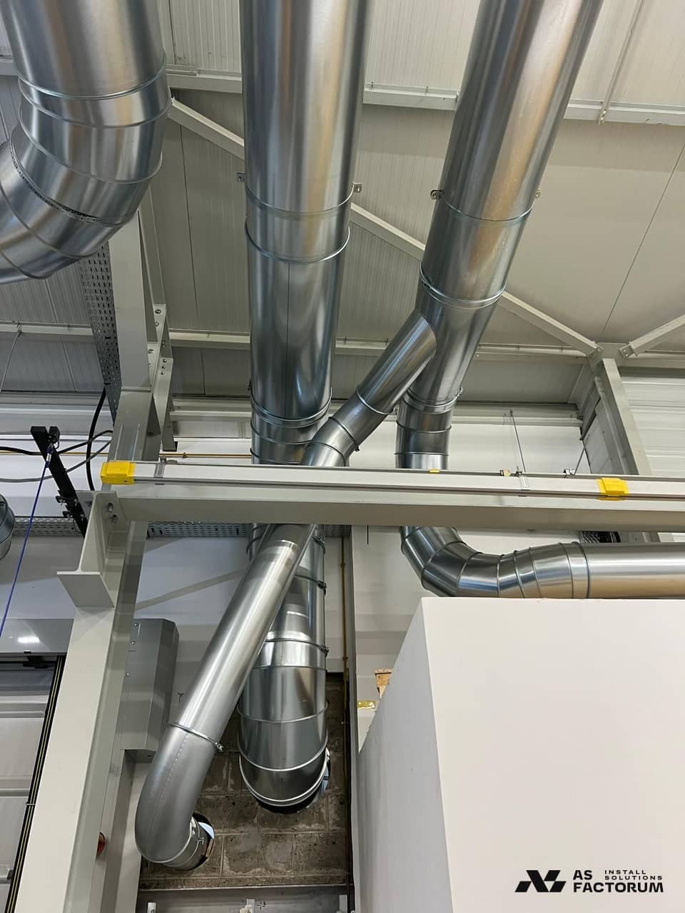 Vertical round ducts with a Y-branch and elbows, fixed to a steel frame