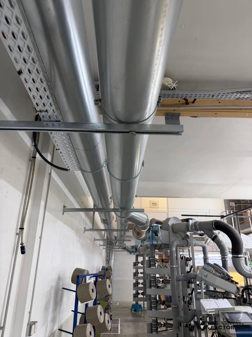 Ventilation ducts running above textile machines and spools of yarn