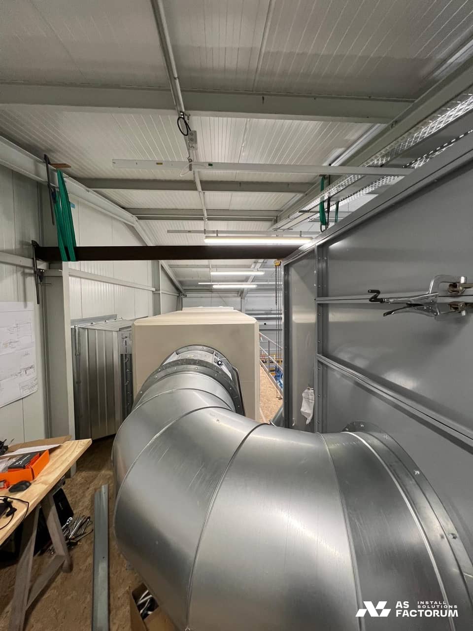 Large duct elbow entering a cream-coloured unit fitted with flanges