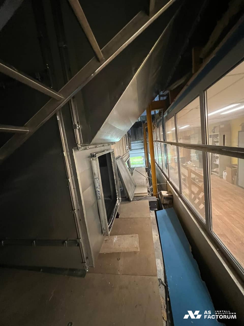 Inside a large metal ventilation duct with an access door beside a glazed wall