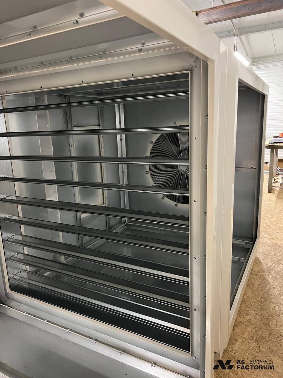 Inside a ventilation unit, showing louvre blades and an axial fan