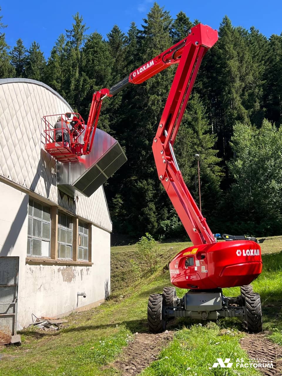 Red boom lift positioning a louvred unit on a roof