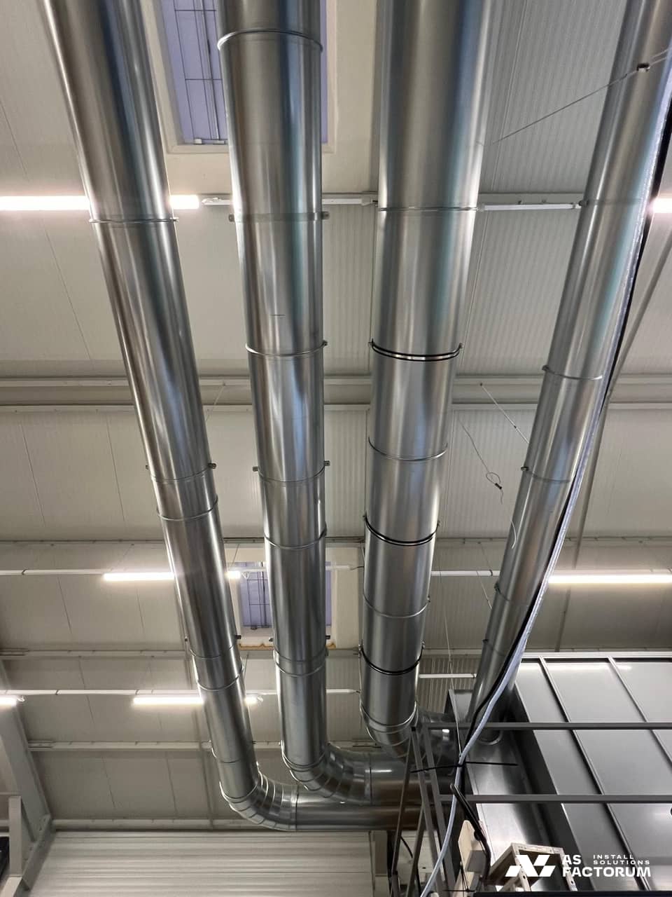 Network of round galvanised ducts crossing the hall, fixed beneath the roof