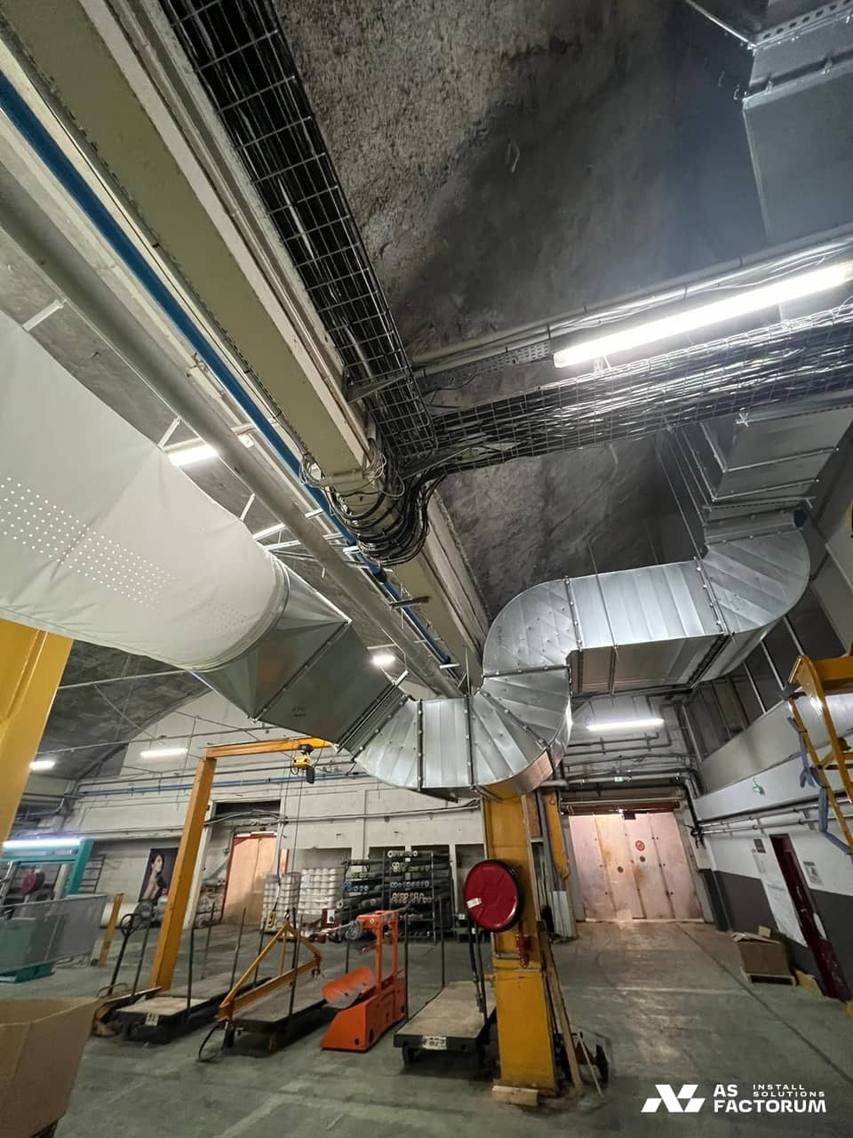 Fabric duct connected to rectangular ducts with a bend in a production hall