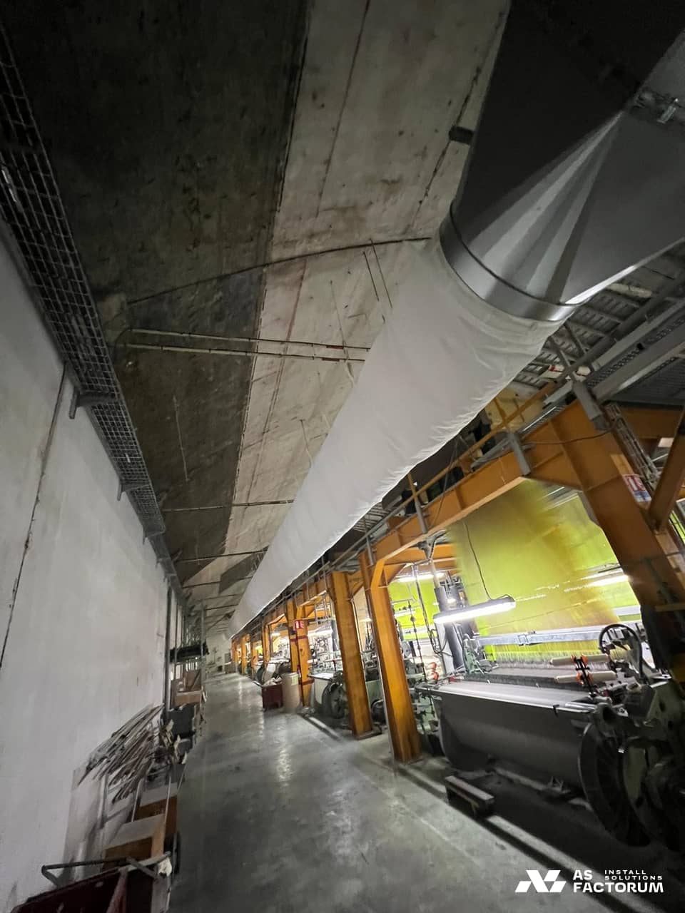 White fabric duct connected to a metal cone above a production hall
