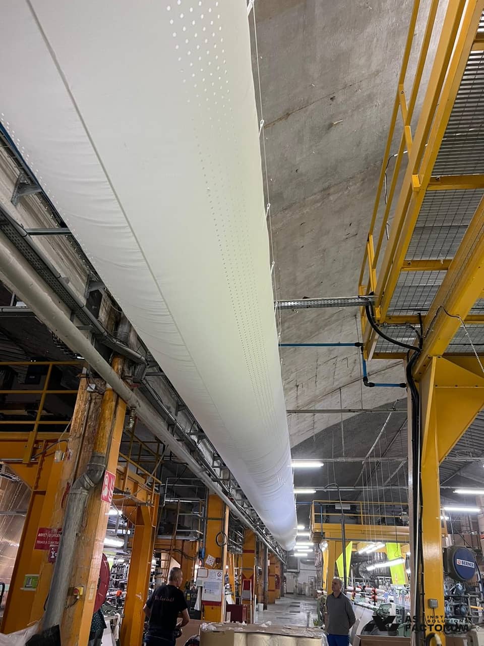 White fabric air distribution duct suspended in a textile production hall
