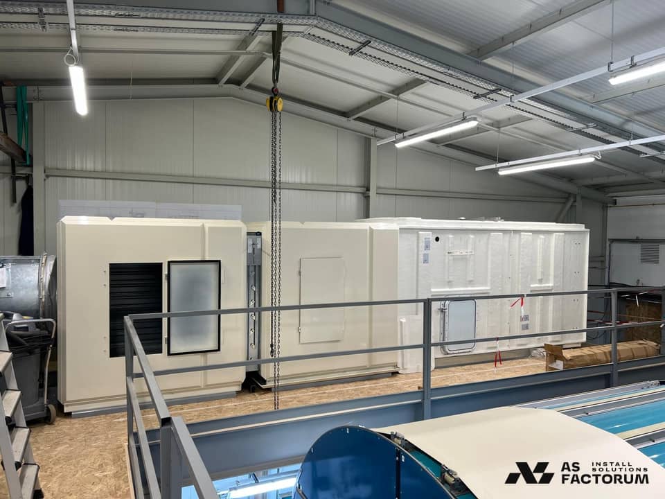 Cream and white air-handling units on a mezzanine, with a hoist mounted above